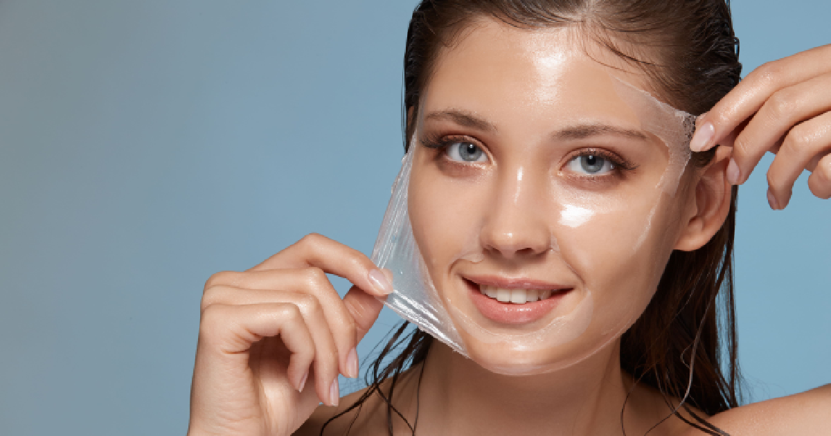 Smiling young woman peeling off a clear facial mask, revealing smooth and glowing skin, symbolizing the rejuvenating effects of chemical peels in Columbia, SC